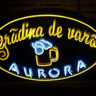 Firma exterioara realizata pe un suport de tabla galvanizata si vopsita, decorata cu autocolant si cu tub de neon modelat deasupra.