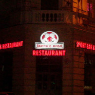 Firma exterioara realizata pe un suport de tabla galvanizata si vopsita, decorata cu autocolant si cu tub de neon modelat sub litere. RESTAURANT